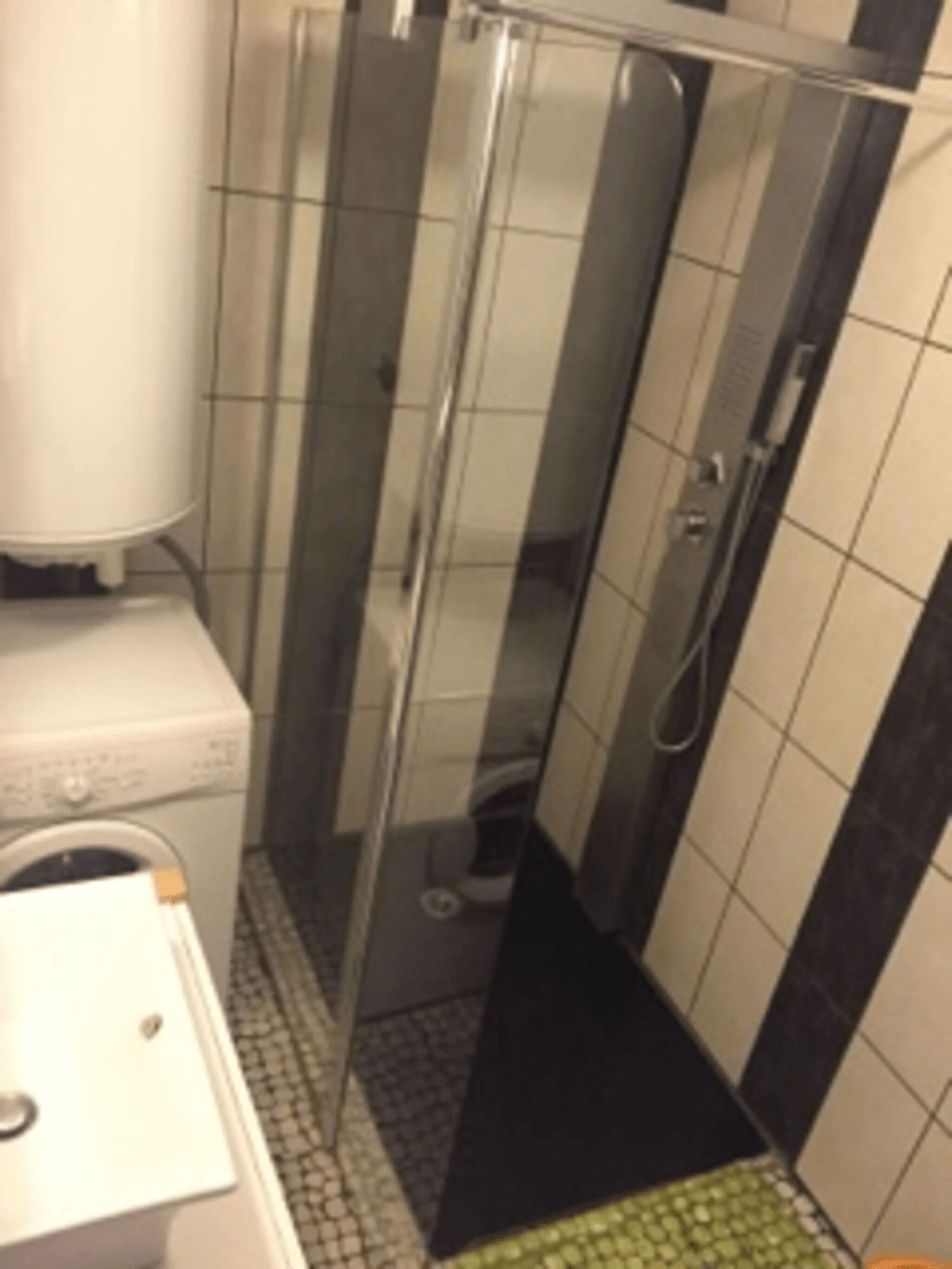 Une salle de bain compacte avec une douche à parois de verre, un lave-linge et des toilettes.