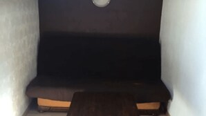 A small, dark-colored room with a wooden floor, a dark-colored sofa, and a small table. - Apt British under the slopes (APT N°21) (Roanne)