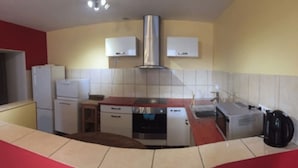 Une cuisine de taille réduite, équipée d’une cuisinière, d’un évier et de deux réfrigérateurs blancs.