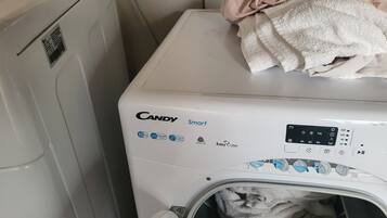 En tvättmaskin med frontmatning, ett kontrollpanel, ett vitt hölje och en hög med vita handdukar ovanpå.