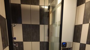 Une salle de bain avec un carrelage à motifs à carreaux, une douche en verre, des toilettes et un porte-serviettes.