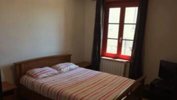A single bed with a striped bedspread in a room with a window and a radiator.
