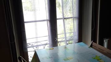 Une pièce avec une table recouverte d’une nappe à motifs de cactus, une fenêtre avec des rideaux et une chaise.
