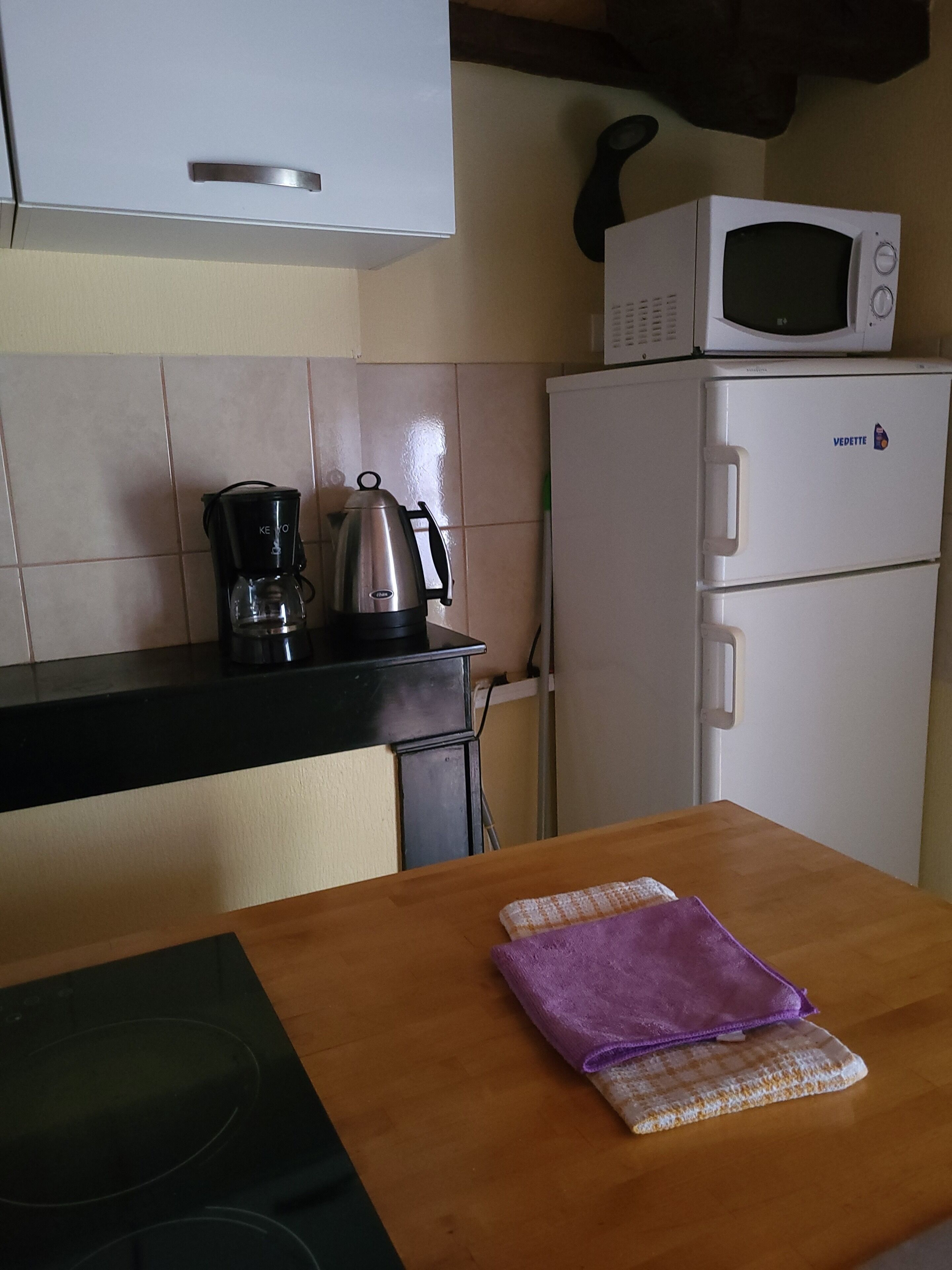 Cozinha equipada com micro-ondas, cafeteira e frigorífico.