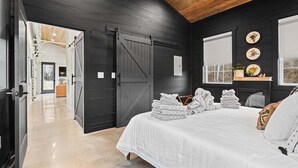 Une chambre avec un grand lit, un plafond en bois et une porte coulissante de style grange.