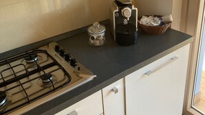 A modern kitchen with a gas stove, a coffee maker, and a basket on the countertop. - Cassino-two-room apartment-park rondo (Cassino)