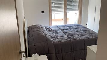 Une chambre à coucher comprenant un lit, une table de chevet, une armoire et une fenêtre avec des stores.