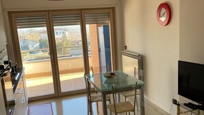 A modern kitchen with a dining area, a TV, and a view of the outside. - Cassino-two-room apartment-park rondo (Cassino)