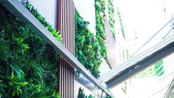 A narrow outdoor corridor with vertical gardens, a metal beam structure, and a seating area with a table and chairs.