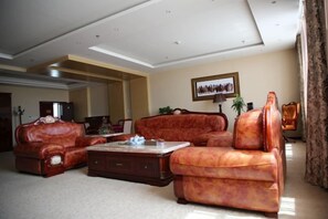 A spacious living room with a large sofa set, a coffee table, and a framed picture on the wall. - Wulagai Guest House (East Ujimqin Banner)