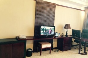 A hotel room with a TV, desk, chair, lamp, and a small table with a book. - Wulagai Guest House (East Ujimqin Banner)