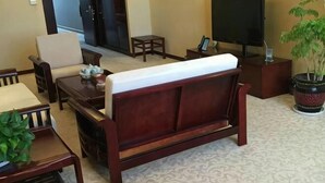 Un salon avec un canapé, un fauteuil, une table basse, un téléviseur et une plante en pot.