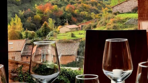 Ein Tisch mit Weingläsern und Blick auf eine gebirgige Landschaft.