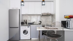 A compact kitchen with a refrigerator, washing machine, microwave, and a sink. - Tangerine 1-Bedroom Apartment in Larnaca (Larnaca)