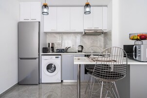 A compact kitchen with a refrigerator, washing machine, microwave, and a sink.