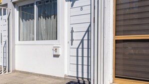 A white building with a number 5 door, a window with curtains, and a metal gate. - Tangerine 1-Bedroom Apartment in Larnaca (Larnaca)