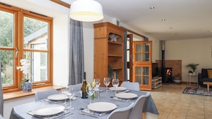 Un coin repas avec une table dressée pour six personnes, une bibliothèque en bois et une cheminée.
