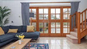 Un salon avec un canapé, une table basse et une vue sur l’extérieur, accessible par une porte vitrée.