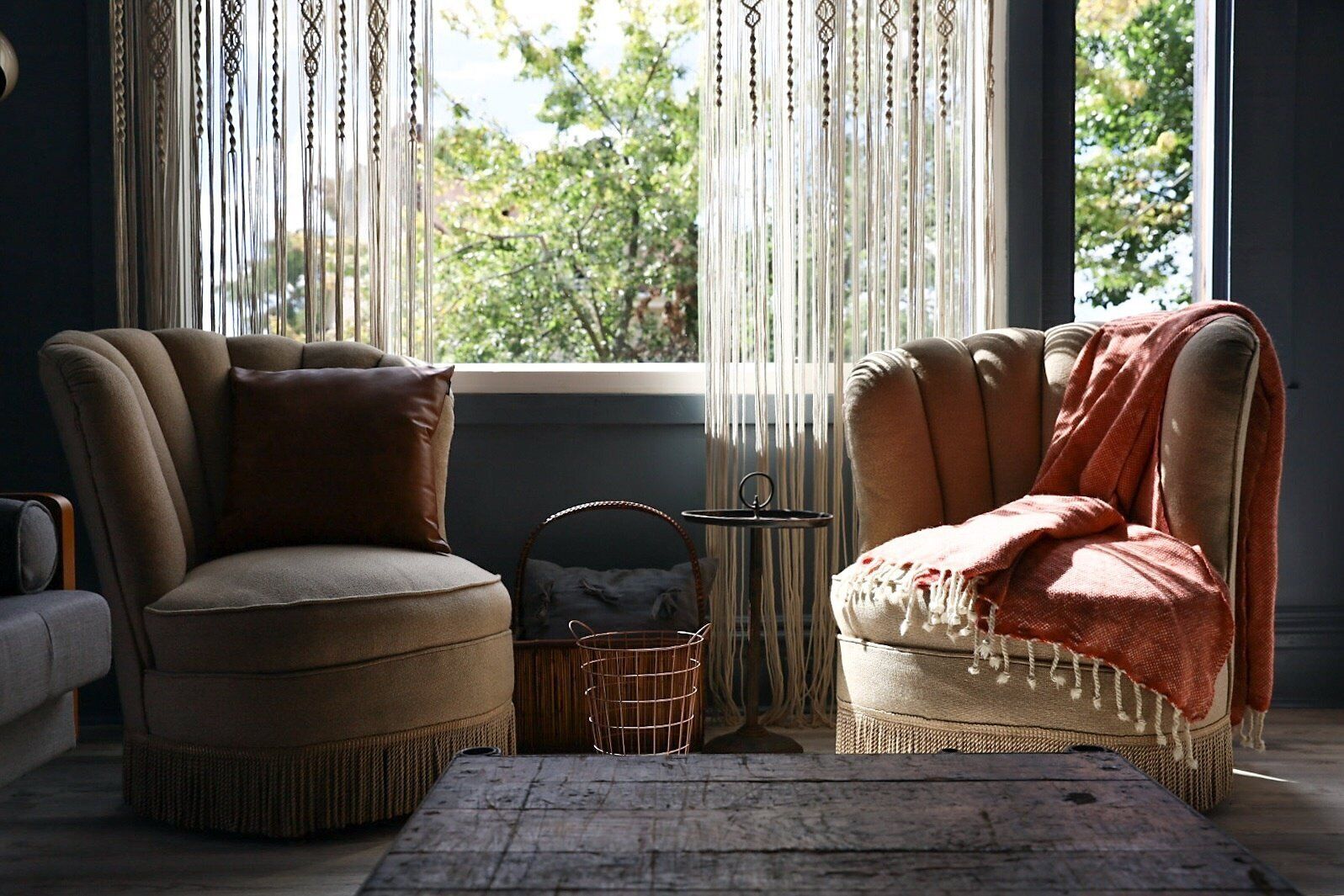 Una sala de estar acogedora con dos sillones, una mesita y una cesta.