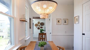 A dining area with a wooden table, chairs, a hanging light fixture, and wall-mounted baskets. - Yinz Retreat, Above the City Home (Pittsburgh)