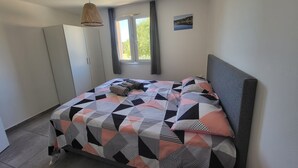 Une chambre à coucher comprenant un lit, une armoire, une fenêtre avec des rideaux et un luminaire suspendu.