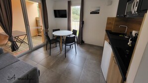 Une cuisine compacte avec un coin repas, un téléviseur fixé au mur et un balcon avec vue.