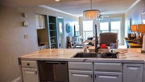 A kitchen with a central island, stainless steel appliances, and a chandelier. - Seville 602: Cozy 2-Bedroom Ocean View Condo (South Padre Island)