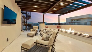 A rooftop terrace with outdoor seating, a fire feature, and a view of the cityscape. - The Castle 8 Bedroom Home (St. George)