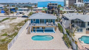 Una propiedad frente a la playa con piscina, terraza cubierta y vistas al océano y al puerto deportivo.