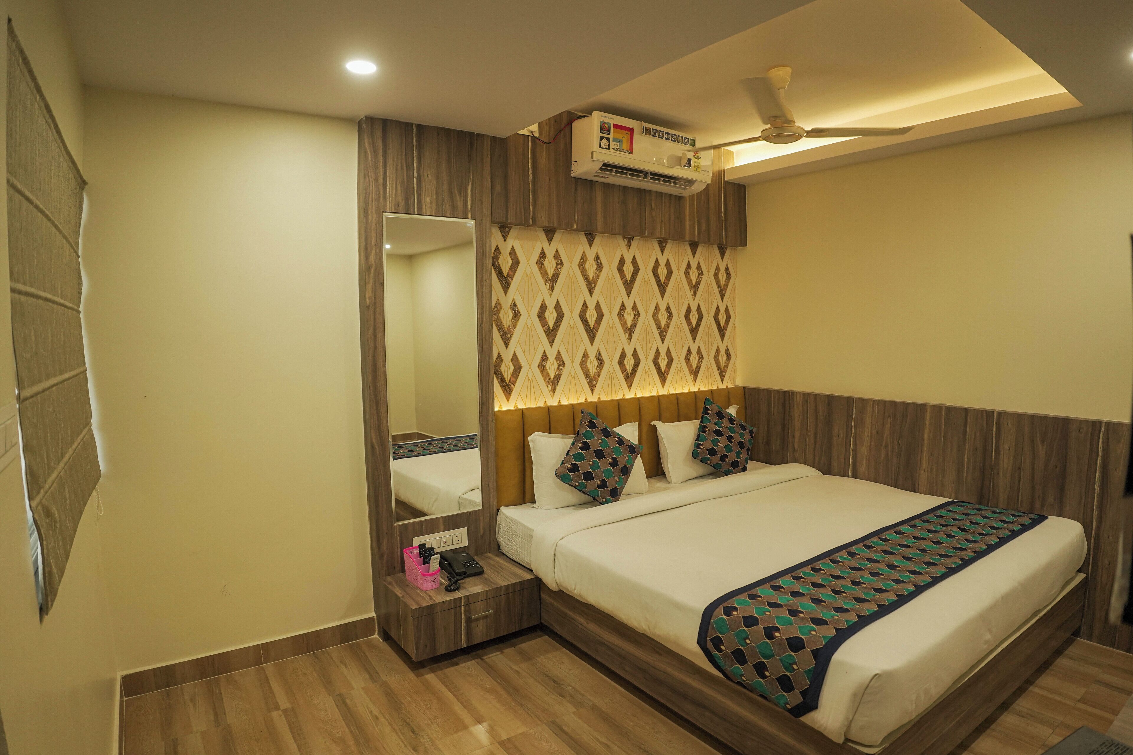 Una habitación de hotel con cama, mesita de noche, espejo, ventilador de techo y aire acondicionado.