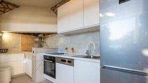 Een moderne keuken met witte kasten, een roestvrijstalen koelkast, een inbouwoven en een vaatwasser.