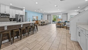 Een moderne keuken met een centraal eiland, barstoelen en een eethoek met stoelen en een tafel.