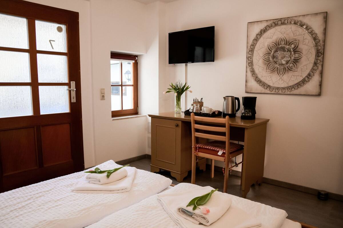 A hotel room with two beds, a desk, a TV, and a decorative wall piece.