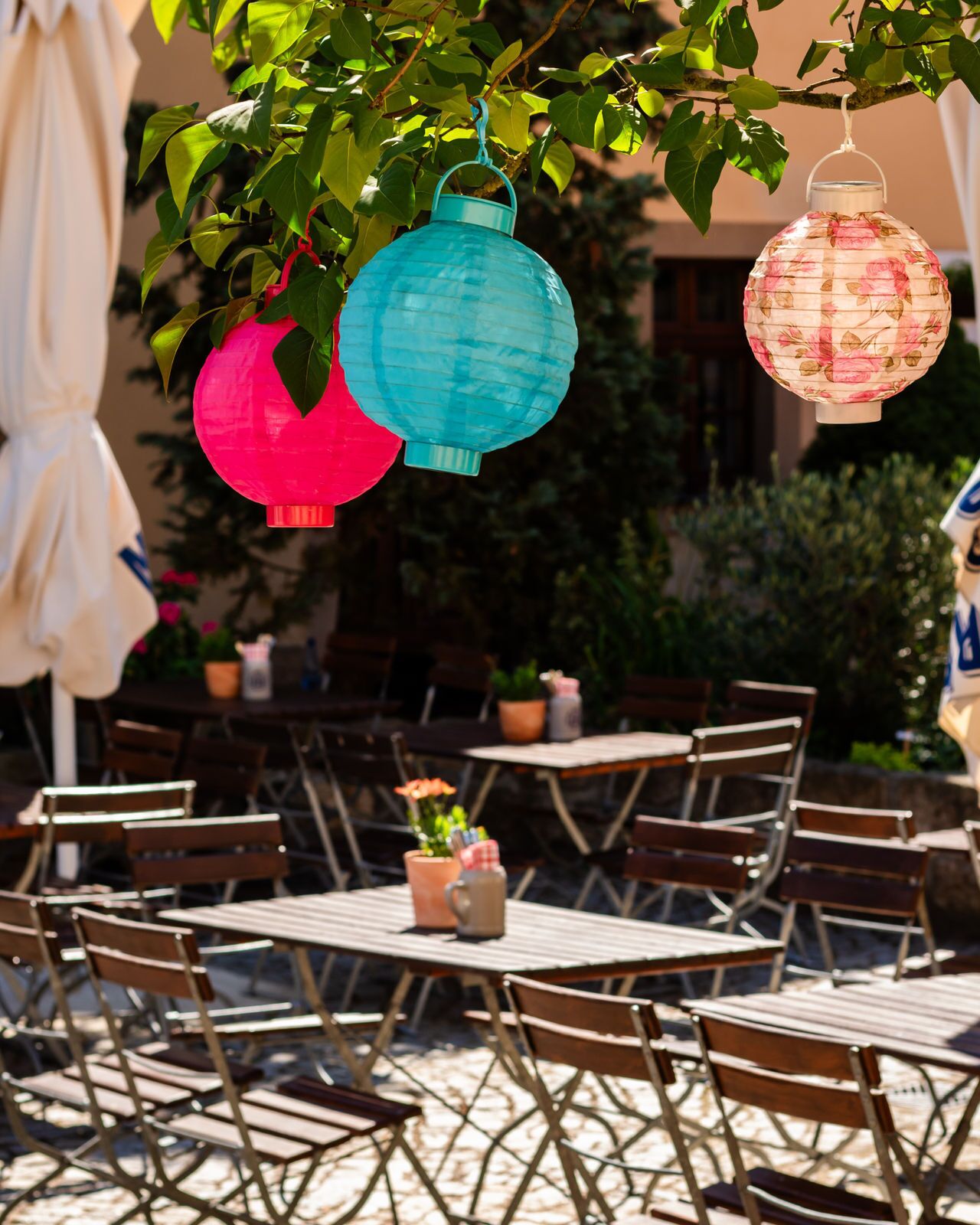 Outdoor seating with tables and chairs, a hanging lantern, and a potted plant.