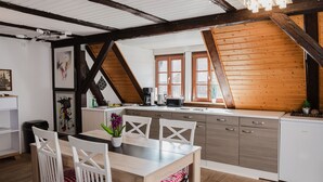 Una cocina moderna con techo de madera, armarios blancos y un comedor con sillas y mesa blancos.