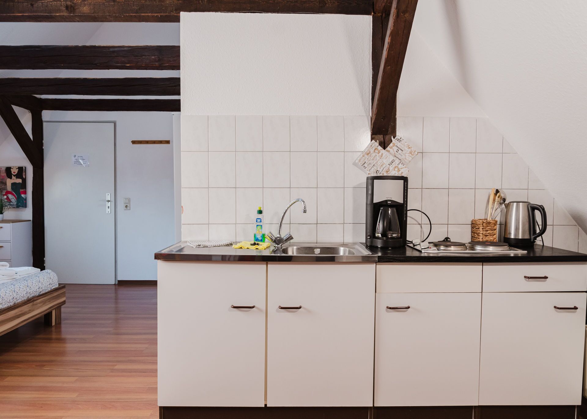 A modern kitchen with white cabinets, a black countertop, and a coffee maker.