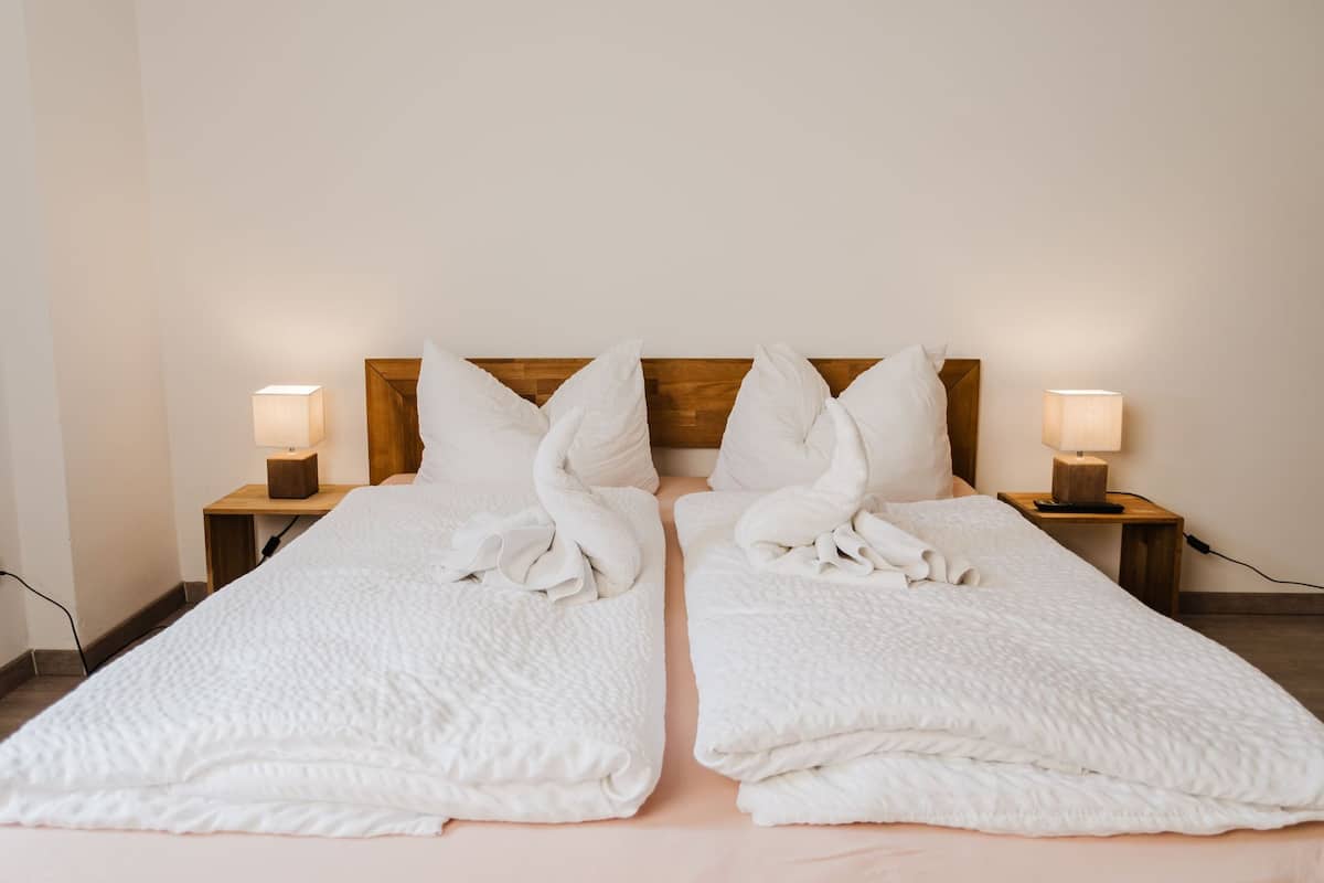 A double bed with white linens and pillows, two bedside tables with lamps, and a wooden headboard.