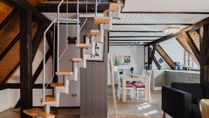 Un loft moderno con escalera de madera, comedor y cocina.