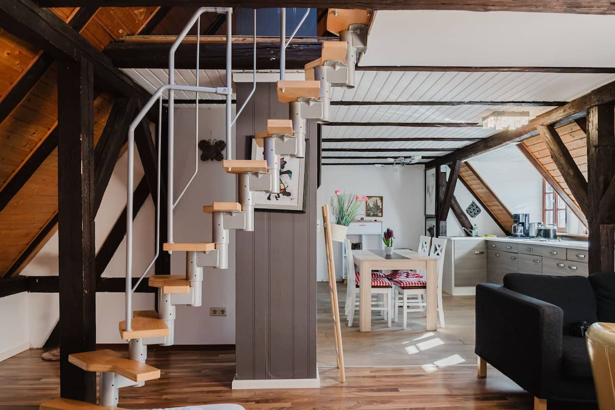 A modern loft with a wooden staircase, a dining area, and a kitchen.