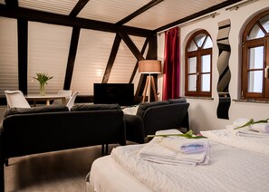 A hotel room with a bed, two armchairs, a desk with a TV, and a window with curtains. - Pension Trobischhof (Dresden)