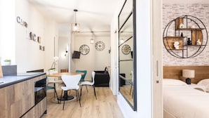 A modern kitchen with a wooden countertop and a dining area with a table and chairs. There are clocks on the wall and a circular shelf with decorative items. - Heart Holiday in Sorrento (Sorrento)