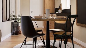 A modern dining area with a round table, black chairs, and a hanging light fixture. - Heart Holiday in Sorrento (Sorrento)