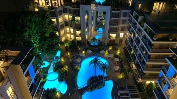 Un hotel de varios pisos con piscina central, zonas de estar al aire libre y un patio luminoso.