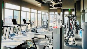 Un gimnasio con cintas de correr, máquinas elípticas y equipo de pesas.
