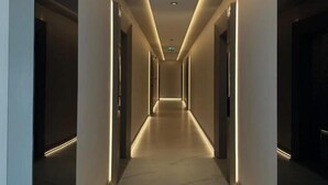 Un pasillo moderno con suelo de mármol e iluminación empotrada.