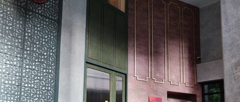 A traditional interior with a green door, a wooden reception desk, and patterned floor tiles.