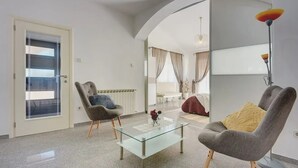 A modern living room with two armchairs, a glass coffee table, and a floor lamp.