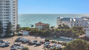 A coastal hotel with a parking lot, ocean view, and adjacent high-rise buildings. - 🐟Spacious Balcony-Across from Beach-2 Pools-Cassine Way 303🐟 (Santa Rosa Beach)