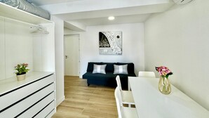 Una sala de estar moderna y minimalista con un sofá, una mesa de comedor y una planta en maceta.
