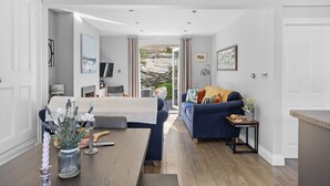 Un salon moderne avec un canapé, une table basse et un téléviseur. Une porte donne accès à un balcon d’où l’on peut admirer le paysage extérieur.